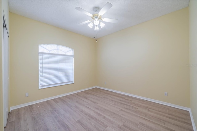 empty room featuring a textured ceiling, baseboards, a ceiling fan, and light wood-style floors