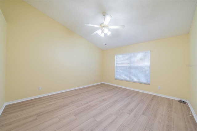 spare room featuring a ceiling fan, vaulted ceiling, light wood-style flooring, and baseboards