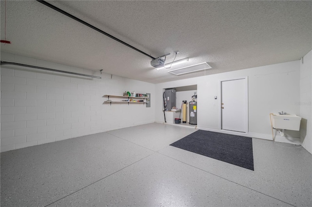 garage with a garage door opener, concrete block wall, electric water heater, and a sink