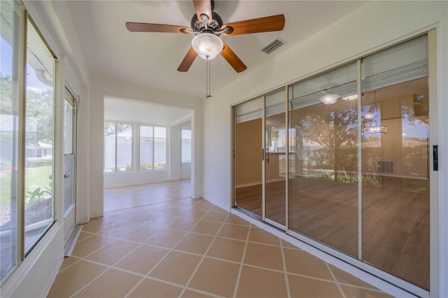 unfurnished sunroom with visible vents and a ceiling fan