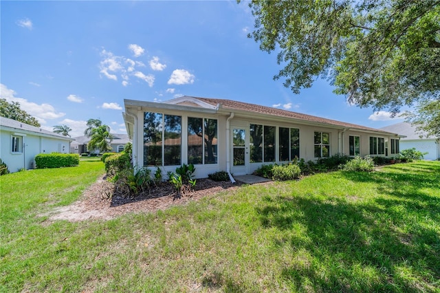 back of house with a lawn and stucco siding