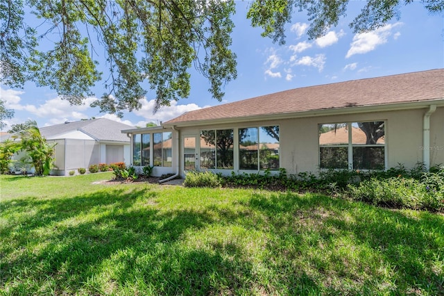 back of house with a sunroom, a lawn, and stucco siding