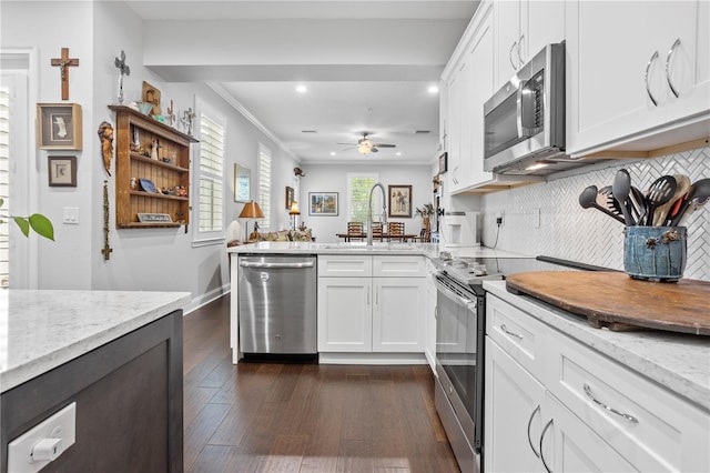 kitchen with tasteful backsplash, white cabinetry, stainless steel appliances, and dark wood-type flooring