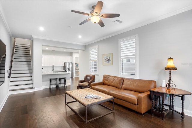 living area with stairway, dark wood finished floors, visible vents, and crown molding