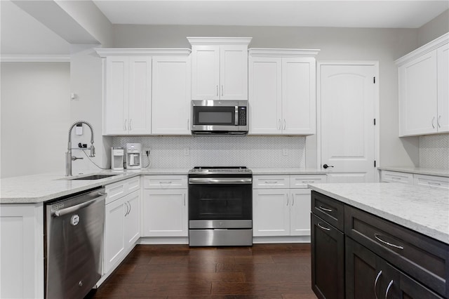 kitchen featuring appliances with stainless steel finishes, a sink, light stone counters, and white cabinets