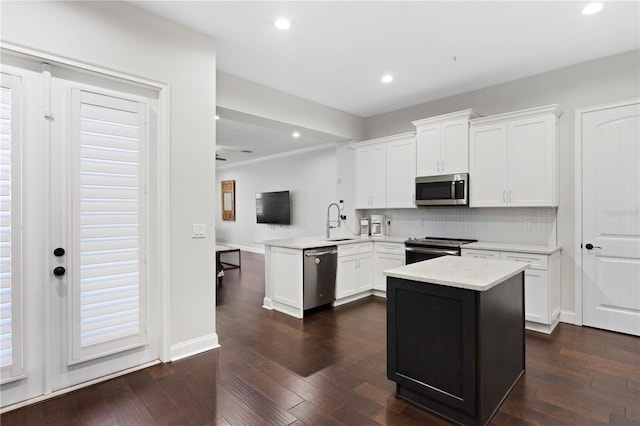 kitchen featuring a peninsula, stainless steel appliances, light countertops, white cabinetry, and a sink