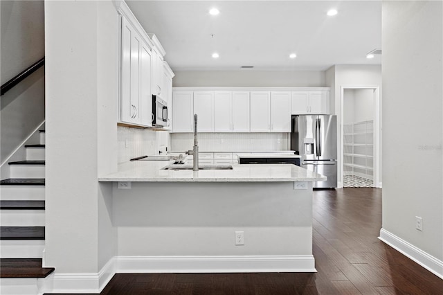 4606 W Fig St Unit 4, Tampa, FL 33609 - kitchen with stainless steel appliances, a sink, baseboards, a peninsula, and white cabinetry