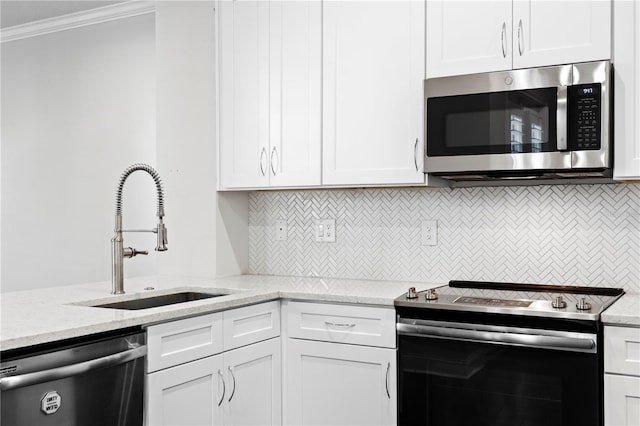 4606 W Fig St Unit 4, Tampa, FL 33609 - kitchen featuring appliances with stainless steel finishes, a sink, white cabinets, decorative backsplash, and ornamental molding