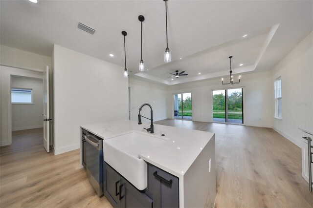 kitchen with ceiling fan with notable chandelier, pendant lighting, a kitchen island with sink, and light hardwood / wood-style floors