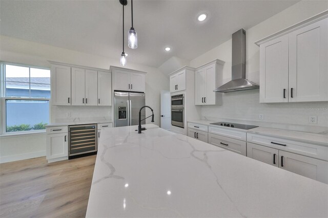 kitchen with white cabinetry, wine cooler, wall chimney exhaust hood, stainless steel appliances, and decorative light fixtures