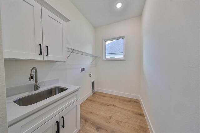 laundry area featuring sink, hookup for an electric dryer, cabinets, hookup for a washing machine, and light hardwood / wood-style floors