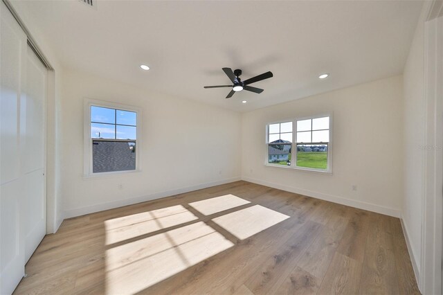 spare room with light wood-type flooring, ceiling fan, and a healthy amount of sunlight