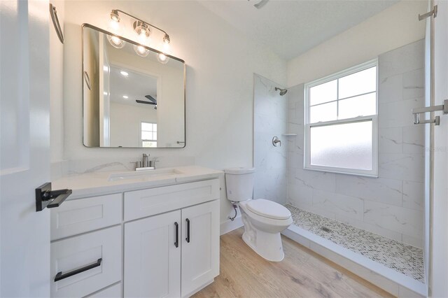 bathroom featuring a tile shower, vanity, toilet, and hardwood / wood-style flooring