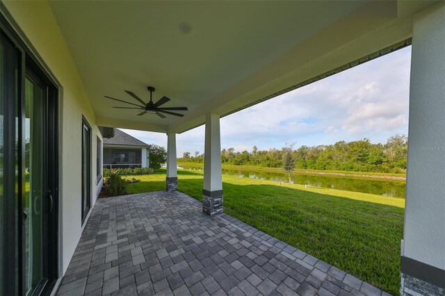 view of patio with a water view and ceiling fan