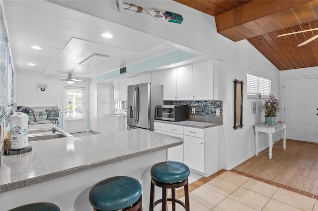 kitchen featuring kitchen peninsula, appliances with stainless steel finishes, sink, white cabinets, and light hardwood / wood-style floors