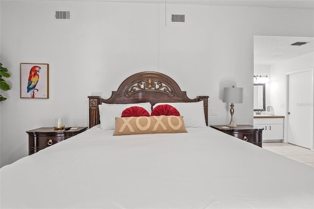 bedroom featuring connected bathroom, light tile patterned floors, and a textured ceiling