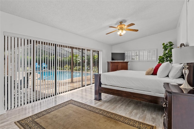 bedroom featuring access to exterior, a textured ceiling, ceiling fan, wood-type flooring, and lofted ceiling