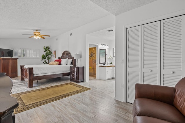 bedroom featuring lofted ceiling, ceiling fan, a textured ceiling, connected bathroom, and light hardwood / wood-style floors