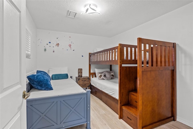 bedroom with light hardwood / wood-style floors and a textured ceiling