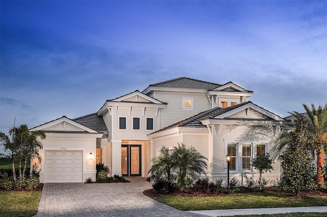 view of front of house featuring a garage, decorative driveway, and stucco siding