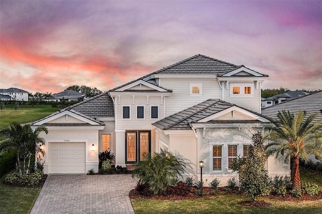 view of front of house with a garage, driveway, a tiled roof, and stucco siding