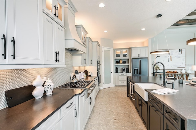 kitchen featuring stainless steel gas stovetop, decorative backsplash, a sink, high end black refrigerator, and premium range hood