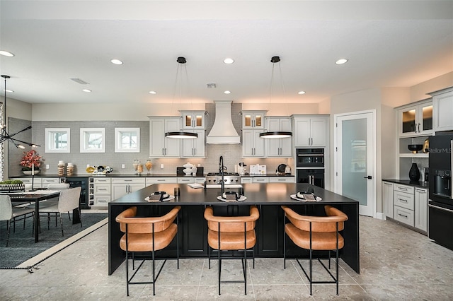 kitchen featuring decorative backsplash, dark countertops, wine cooler, a breakfast bar area, and premium range hood