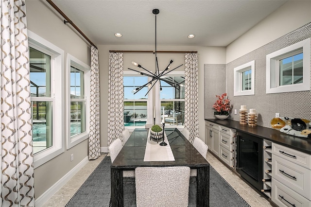 dining space featuring wine cooler, a textured ceiling, baseboards, and recessed lighting