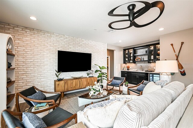 living room with sink, hardwood / wood-style floors, and brick wall