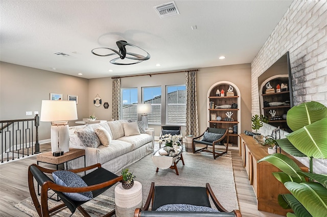 living room featuring built in features, light hardwood / wood-style floors, and a textured ceiling