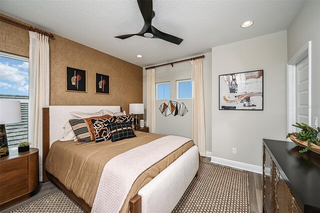 bedroom featuring dark wood-type flooring, ceiling fan, a textured ceiling, and multiple windows