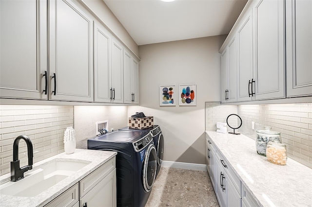 laundry room featuring cabinet space, a sink, baseboards, and separate washer and dryer