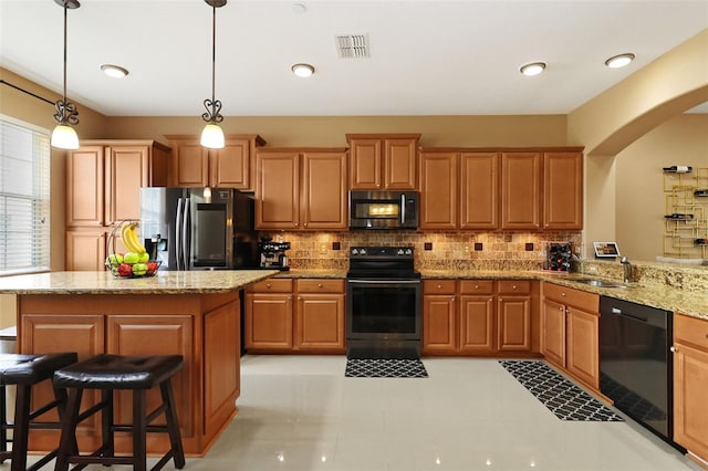 kitchen featuring light stone countertops, backsplash, sink, black appliances, and hanging light fixtures