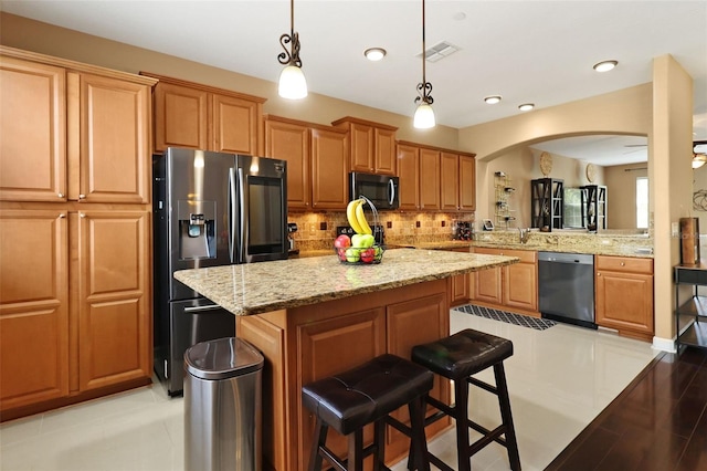 kitchen with ceiling fan, hanging light fixtures, kitchen peninsula, a breakfast bar area, and appliances with stainless steel finishes