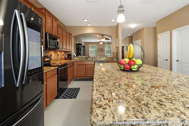 kitchen featuring ceiling fan, sink, light stone countertops, decorative backsplash, and appliances with stainless steel finishes