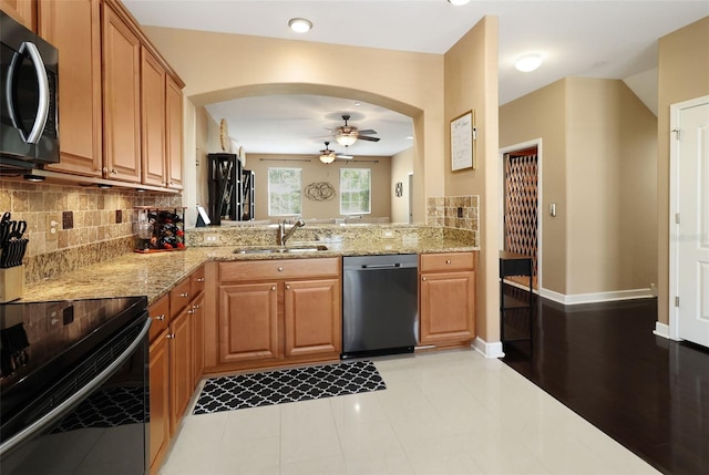 kitchen with sink, ceiling fan, light wood-type flooring, light stone counters, and stainless steel appliances