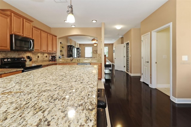 kitchen with a kitchen breakfast bar, tasteful backsplash, ceiling fan, dark wood-type flooring, and electric range