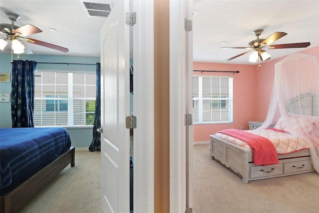 bedroom with light colored carpet, multiple windows, and ceiling fan