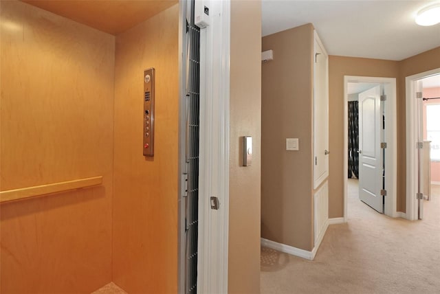 hallway featuring light carpet and elevator