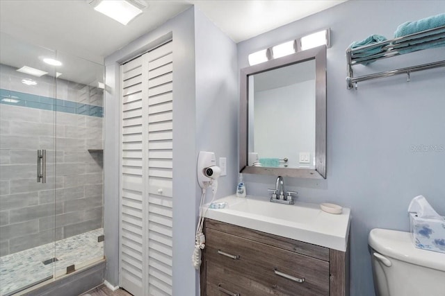 bathroom with an enclosed shower, vanity, and toilet