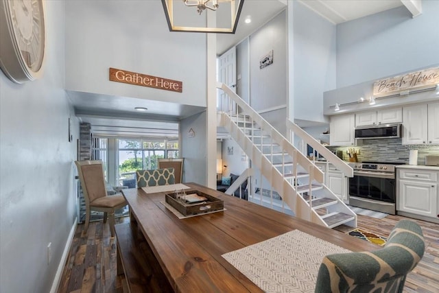 dining space featuring a high ceiling, hardwood / wood-style floors, and an inviting chandelier