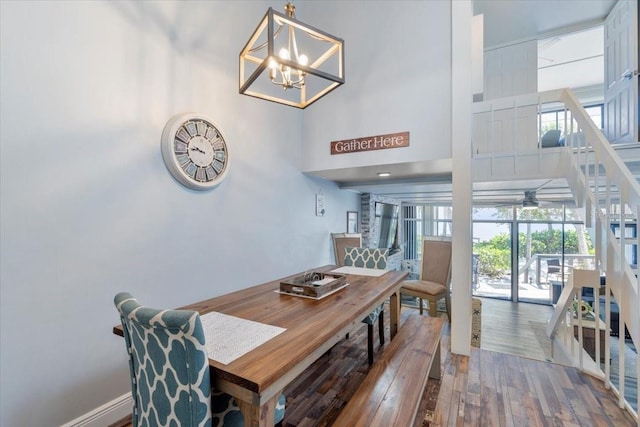 dining area with a towering ceiling, hardwood / wood-style flooring, and a notable chandelier