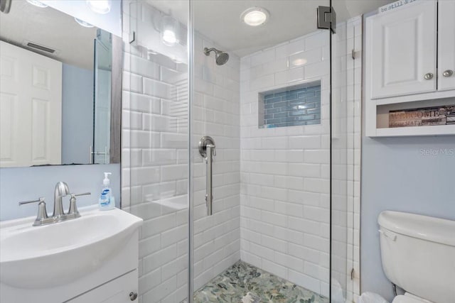 bathroom featuring toilet, a shower with door, and vanity