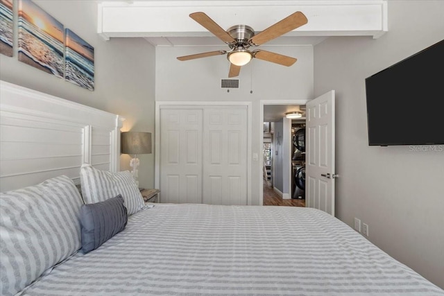 bedroom featuring a closet, ceiling fan, hardwood / wood-style flooring, and stacked washer / dryer