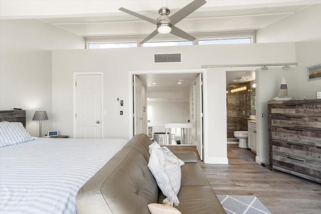 bedroom with a towering ceiling, ensuite bath, ceiling fan, and hardwood / wood-style flooring