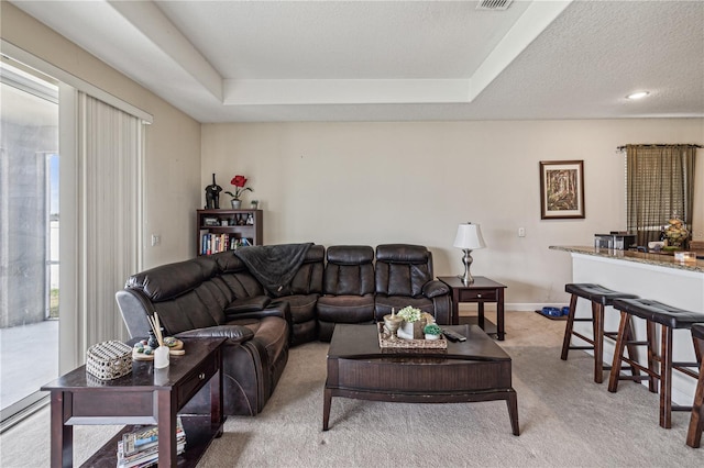 carpeted living room with a tray ceiling and a textured ceiling