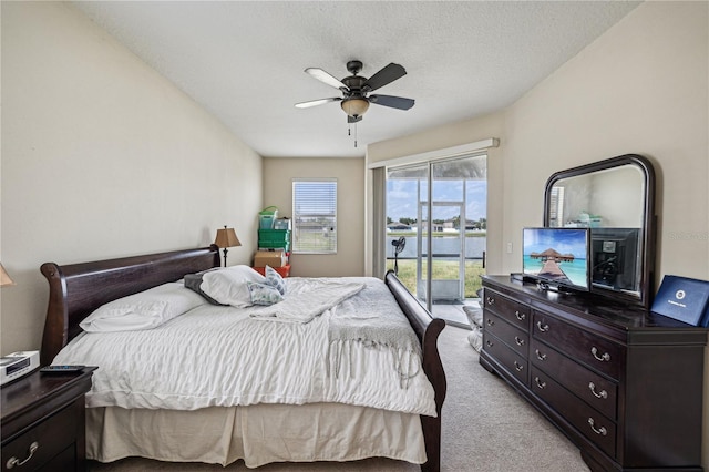 carpeted bedroom with a water view, ceiling fan, and access to exterior