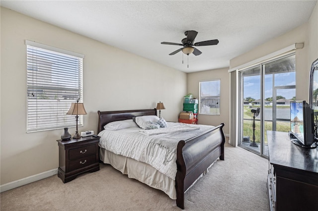 bedroom with ceiling fan, multiple windows, light carpet, and access to outside