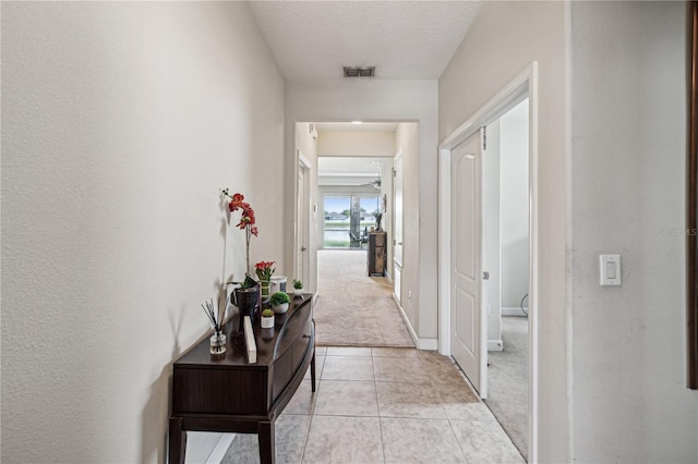 corridor featuring a textured ceiling and light tile flooring