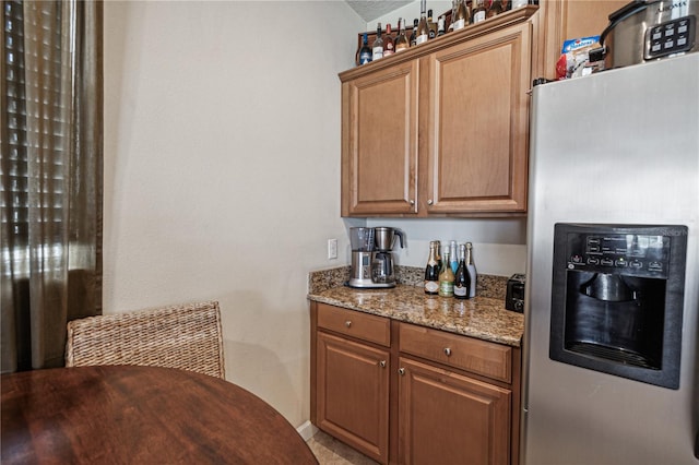 kitchen with light stone counters and stainless steel refrigerator with ice dispenser